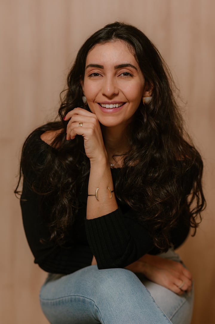 Ana Luiza sorrindo, com a mão no queixo